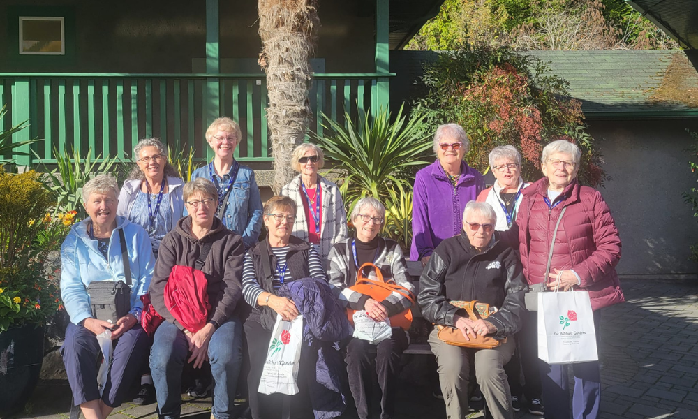 Group of women from a Pro Tours bus tour posing together at Butchart Gardens in Victoria, BC.