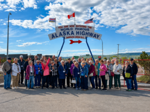 Pro Tours group gathered beneath the Alaska Highway sign in Dawson Creek, British Columbia